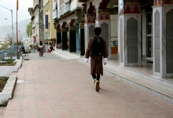 On Thimphu street, a man wearing the traditional &#039;goh&#039; for men.